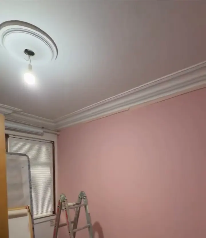 Habitación con la pared pintada de rosa y la moldura del techo repasada