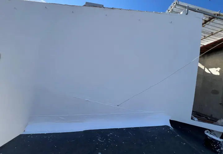 Después: la misma medianera reparada y pintada de blanco