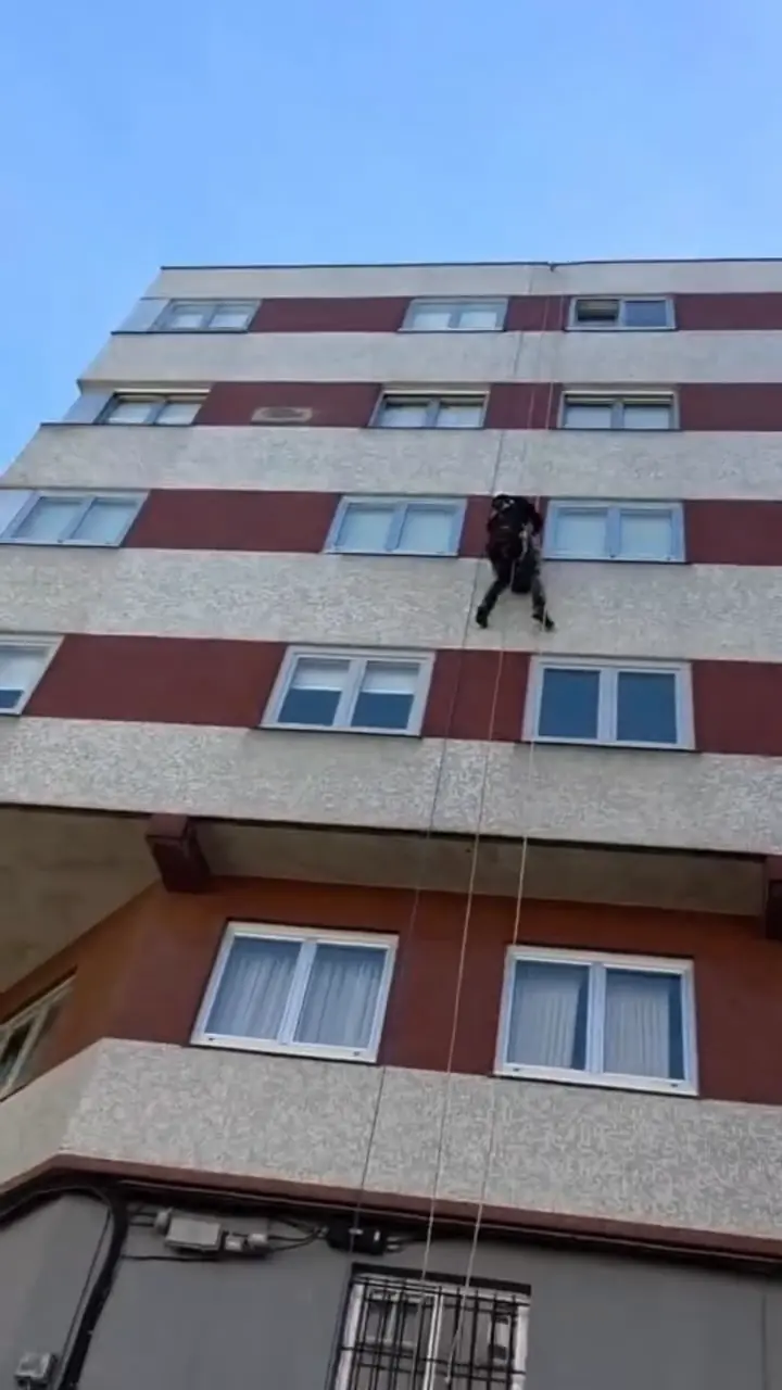 Operario colgado de cuerdas en la fachada de un edificio de viviendas