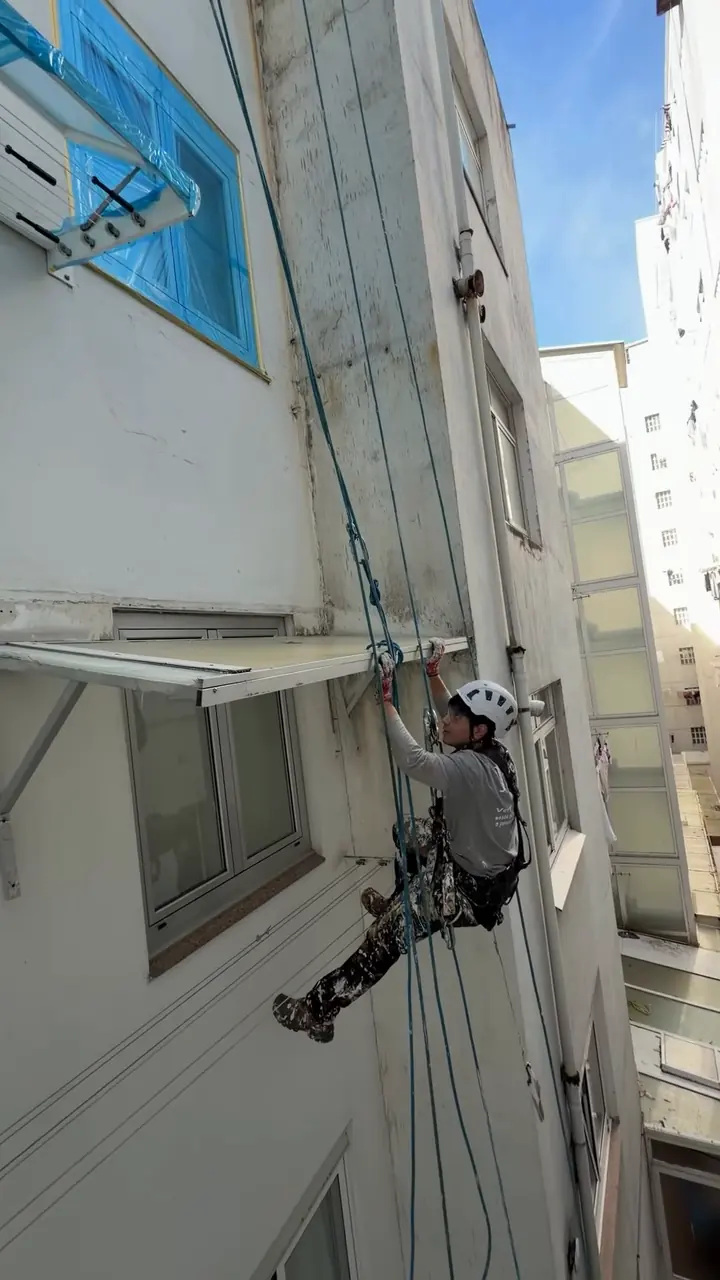 Trabajador de JMI Verticales descolgándose con cuerdas por un patio de luces
